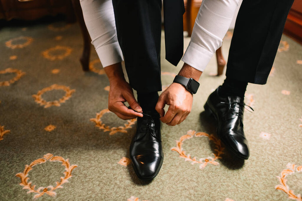 A man in a suit, the groom, close-up puts on shoes, ties his shoelaces - Foto, Bild
