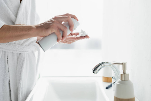 cropped view of man applying shaving foam on hand near sink in bathroom - Foto, imagen