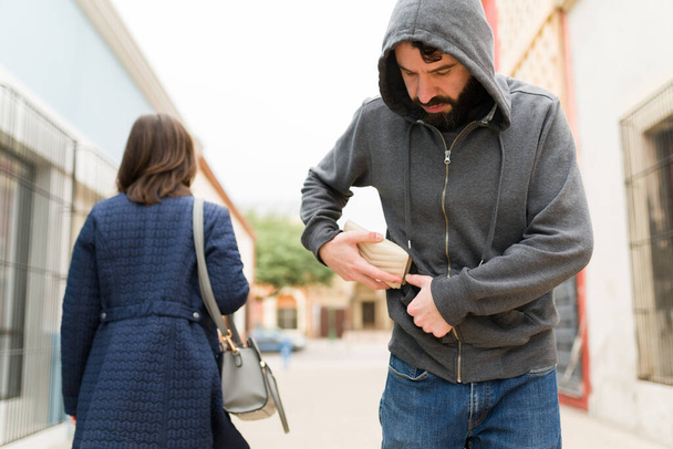 Pickpocket voler de l'argent et un portefeuille à l'arrière d'une femme tout en marchant dans la rue pendant la journée - Photo, image