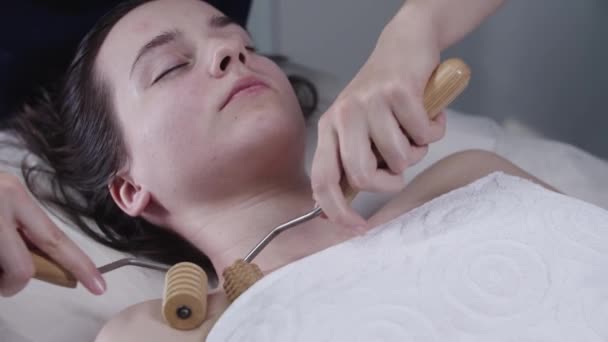 Женщина-массажист, использующая два деревянных ролика на верхней части груди своей клиентки - Кадры, видео