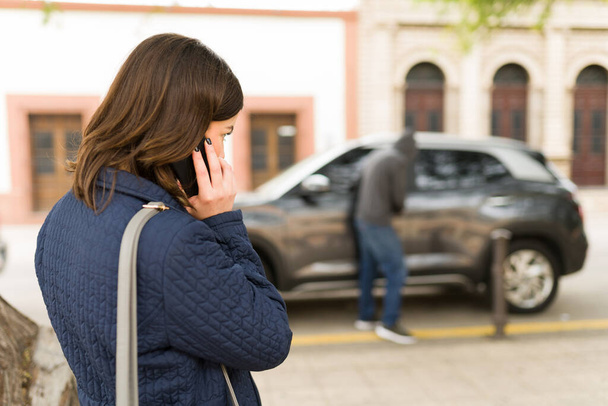 Minä tarvitsen apua. Taustakuva nuoresta naisesta soittamassa hätänumeroon älypuhelimellaan autokaappauksen vuoksi - Valokuva, kuva