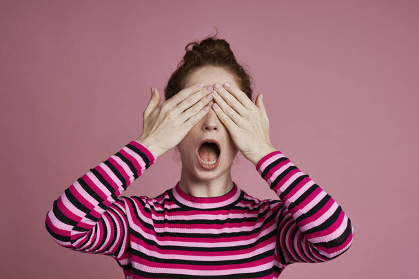 Studio shot of young woman covering eyes and screaming  - Φωτογραφία, εικόνα