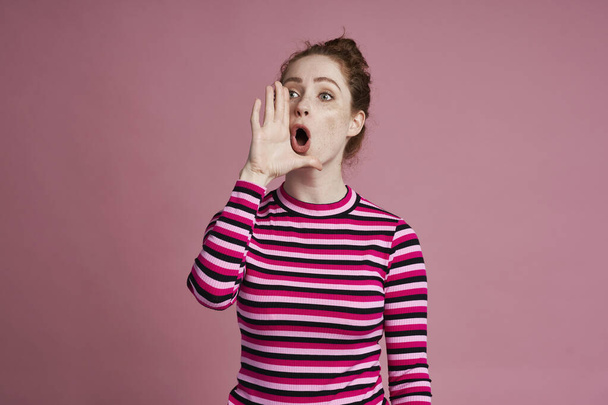 Studio záběr mladé ženy křičí a stojí na růžovém pozadí                                 - Fotografie, Obrázek
