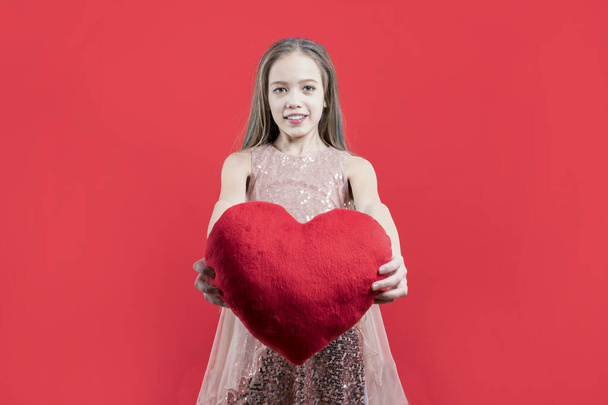 Gratuluję świąt. Słodka dziewczyna trzyma czerwone serce w dłoniach na czerwonym tle. Walentynki. Miłości. Deklaracja miłości. - Zdjęcie, obraz