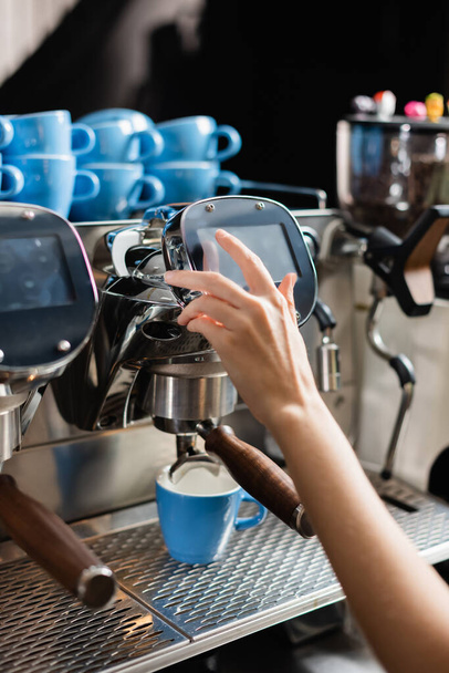 Ausgeschnittene Ansicht von Barista mit Kaffeemaschine in der Nähe von Tassen im Café  - Foto, Bild