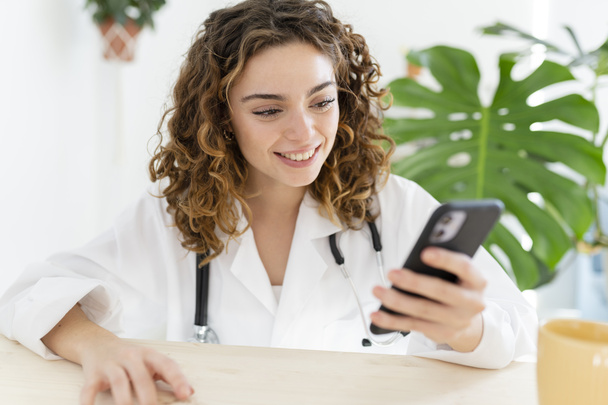 woman doctor, mobile phone, desk - Photo, Image