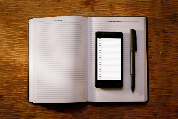 Mobile phone on an open diary or journal - Photo, Image