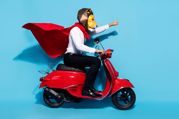 Full body profile side photo of weird lion mask wear red mantle guy ride scooter protect planet isolated over blue color background - Fotografie, Obrázek
