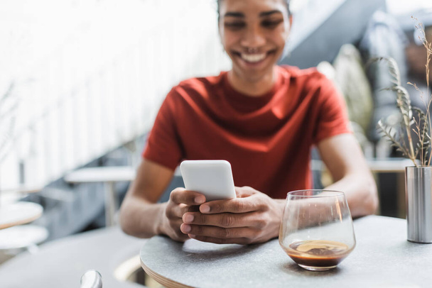 Мобільний телефон в руках розмитого афроамериканця біля келиха кави в кафе
  - Фото, зображення