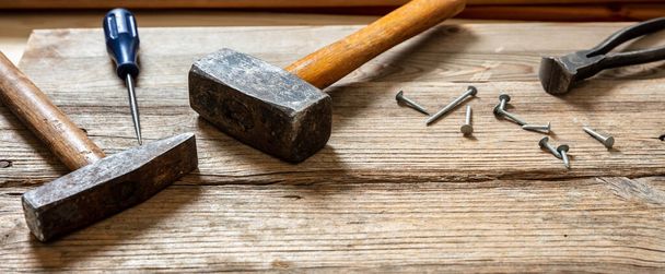 Herramientas de mano usadas, martillo, plincers de martillo y clavo en madera, mesa de banco de carpintero, vista de primer plano - Foto, imagen