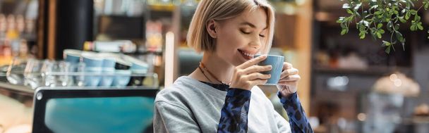 Cheerful woman holding cup of coffee in cafe, banner  - Photo, image