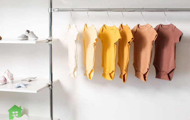 Φορέματα μωρού κρέμονται κοντά στο φως τοίχο στο δωμάτιο - Φωτογραφία, εικόνα