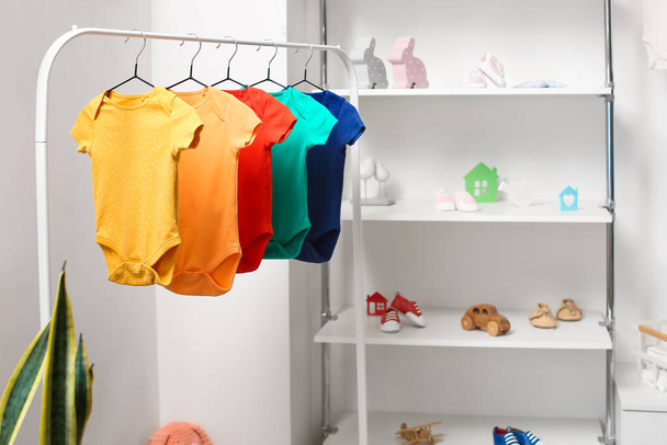 Stojak z kolorowymi dziecięcymi body w jasnym pokoju dziecięcym - Zdjęcie, obraz
