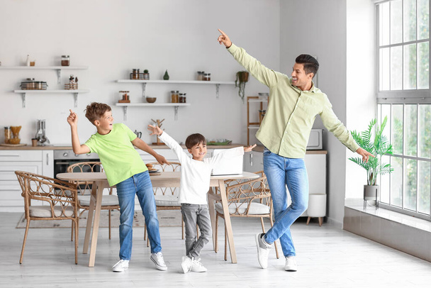 Boldog apa és fiai táncolnak a konyhában. - Fotó, kép