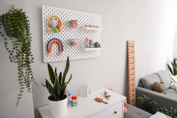 Pegboard gyermekjátékokkal és flakonokkal a világos falon a szobában - Fotó, kép