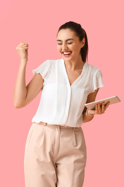 Happy young businesswoman with tablet computer on pink background - Fotó, kép