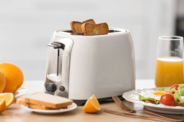 White toaster with tasty breakfast on table in light kitchen - Фото, зображення