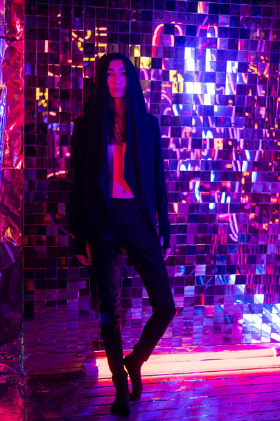 Androgenic model in a hood. Male transgender in studio with neon light. - Foto, afbeelding