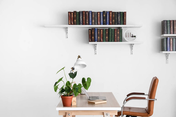 Stůl a knihy na policích zavěšených na stěně v interiéru místnosti - Fotografie, Obrázek