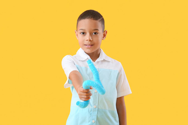 Little African-American boy with blue Pop Tube on yellow background - Photo, Image