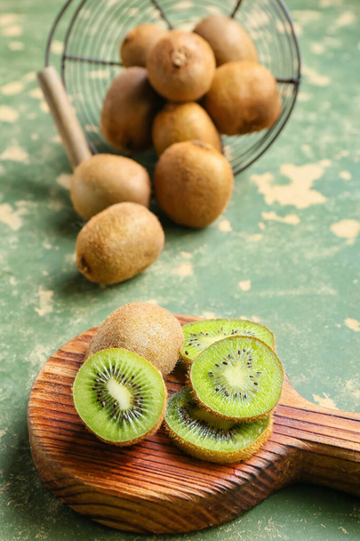 Wooden board with fresh cut kiwi on green background - Photo, image