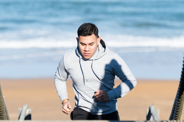 Половина тела латинского мужчины тренируется на пляже - Фото, изображение