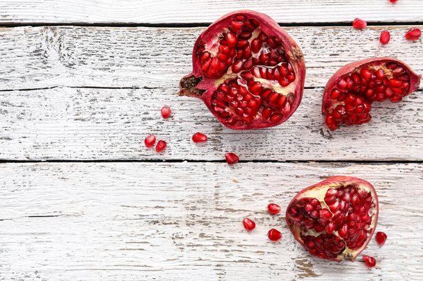 Pieces of fresh pomegranate on light wooden background - Фото, изображение