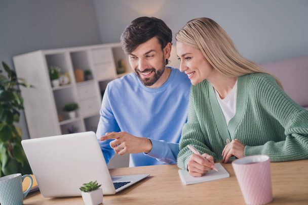 Portrait of two attractive cheerful people using laptop choosing order goods web service at home indoors - Фото, изображение