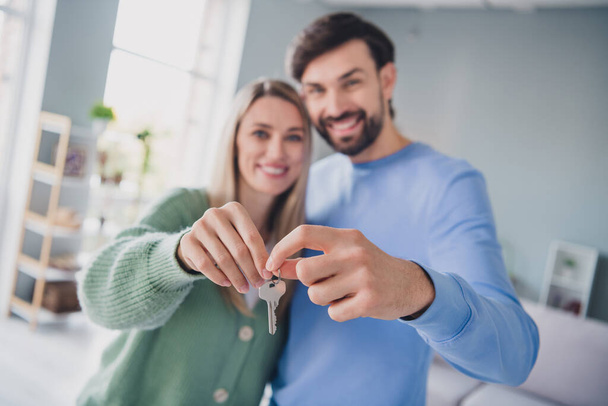 Portrait of two attractive cheerful people partners bonding holding in hands key from new flat at home indoors - Fotoğraf, Görsel