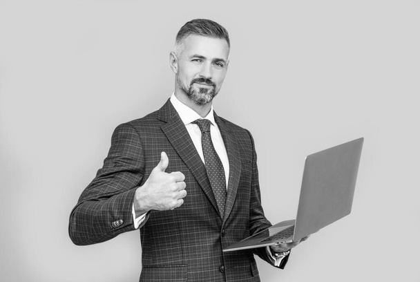 pewny biznesmen człowiek w biznesowym garniturze trzymać komputer pokazać kciuk w górę, sukces - Zdjęcie, obraz