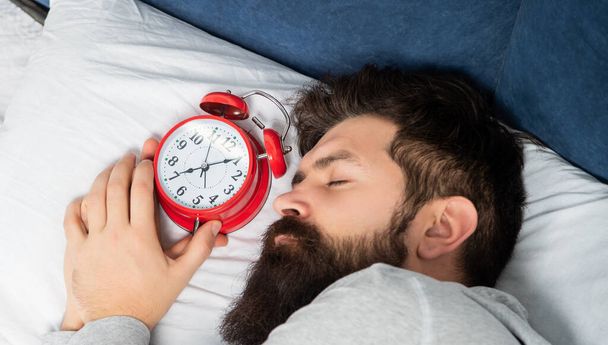 Portrait of man sleeping with alarm clock in bed, sleep time - Zdjęcie, obraz
