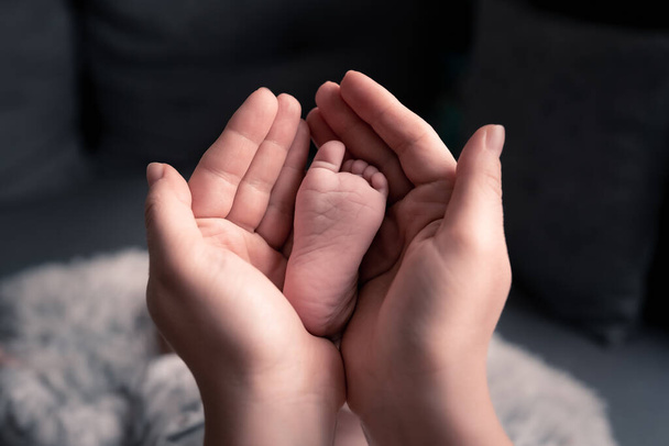 Мать держит ноги новорожденного ребенка на руках, любовь с первого взгляда, ребенок чувствует любовь и безопасность от матери, за жизнь - Фото, изображение