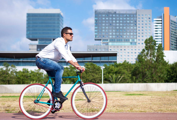 Male with sunglasses riding bicycle in urban city commuting trendy transportation - 写真・画像