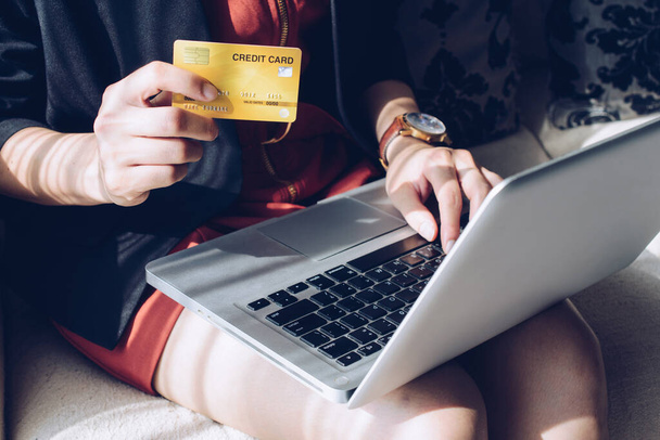 オンラインショッピングのためのラップトップを使用している間、クレジットカードを保持しているビジネス女性の閉鎖。オンラインショッピングは、インターネット上の商人から商品やサービスを購入するプロセスです。. - 写真・画像