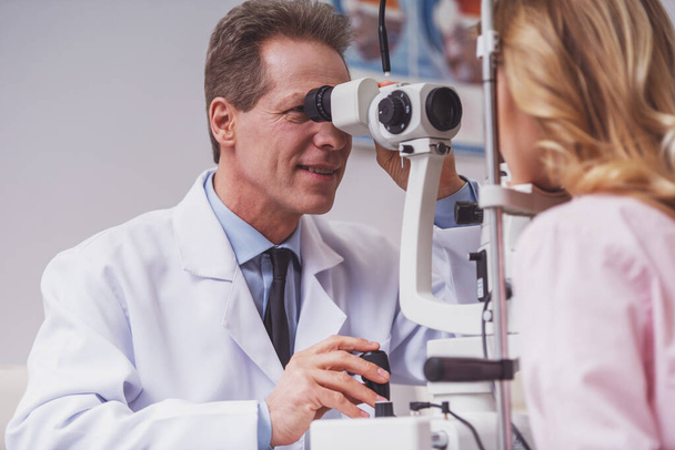 Handsome ophthalmologist examining beautiful woman's eyes with modern equipment - Photo, Image