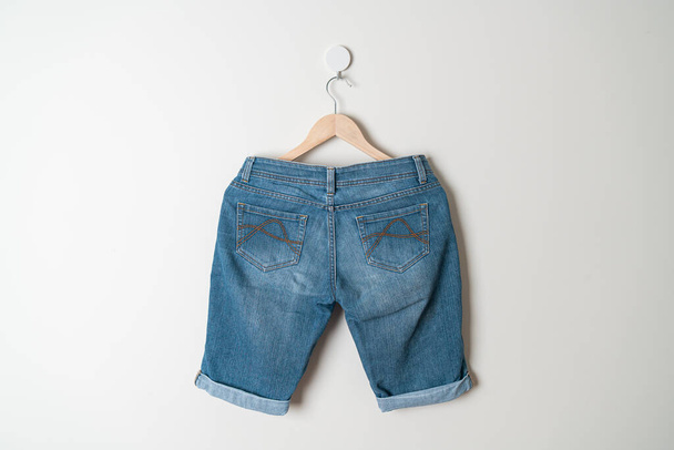 short pants jeans hanging with wood hanger on wall - Фото, зображення