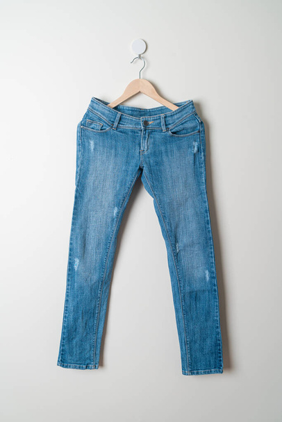 jeans trousers hanging with wood hanger on wall - Foto, Imagem