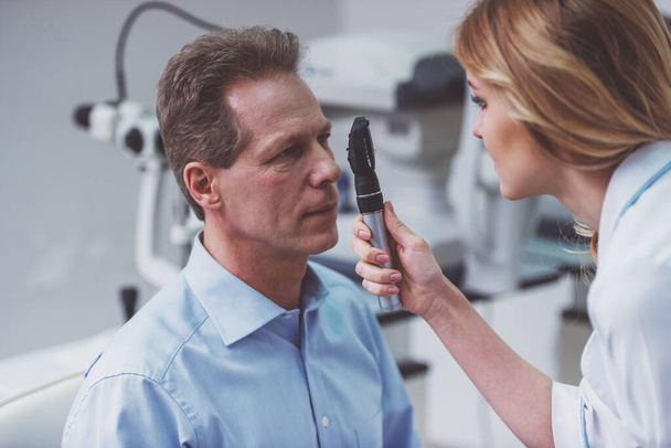 Young beautiful female ophthalmologist examining handsome middle aged man with modern equipment,close-up - Photo, image