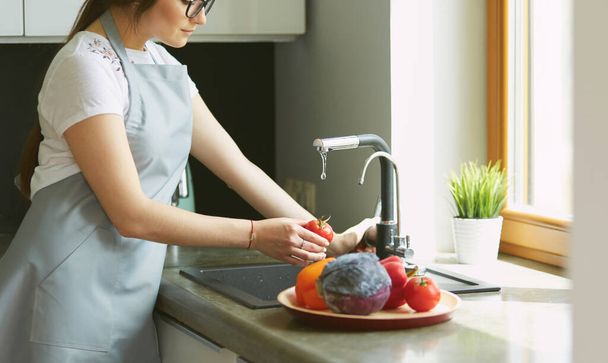 Woman washing tomatoes in kitchen sink close up - Foto, Imagem