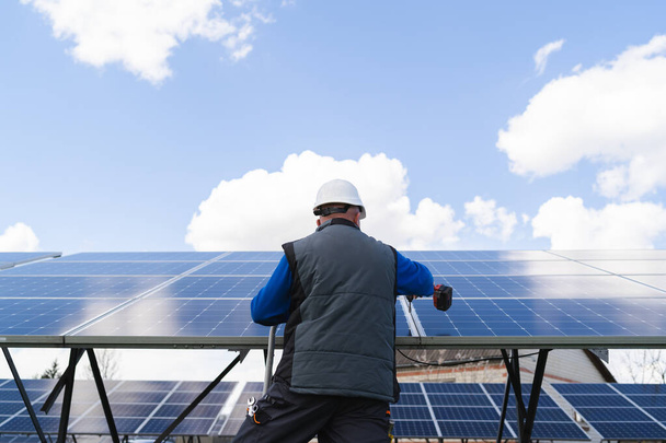 Zadní pohled na člověka pracuje se šroubovákem na solárních panelech - Fotografie, Obrázek