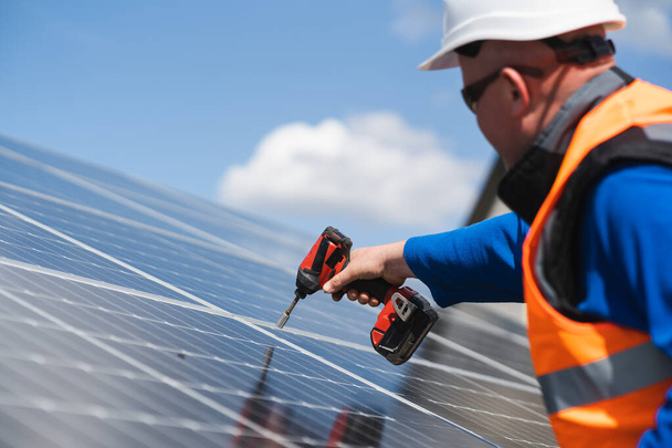 Travailleur avec un tournevis pour fixer le panneau d'une centrale solaire - Photo, image