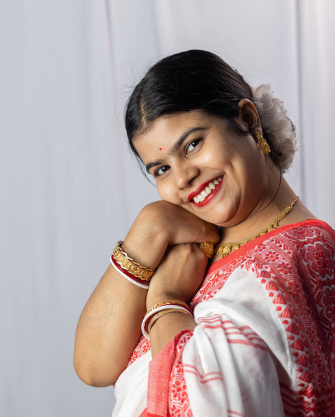 Une Indienne en saree rouge portant des bracelets avec un visage souriant sur fond blanc - Photo, image