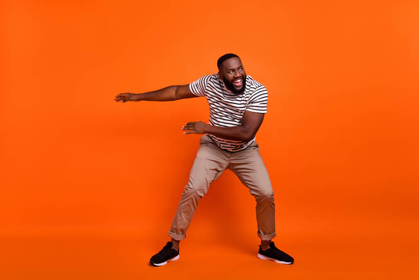 Full body photo of young cheerful african guy good mood dance look empty space isolated over orange color background - Foto, Imagen