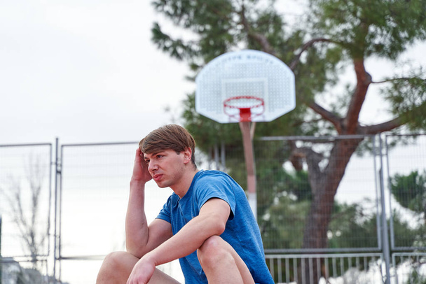 basketball player sitting on the ball on the court - Foto, Imagem