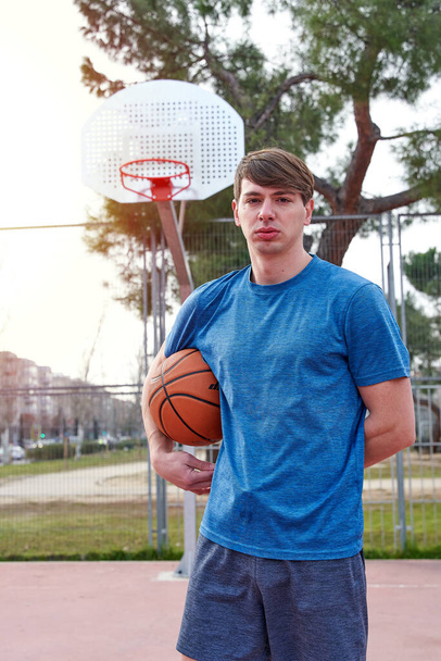 Genç bir sporcu açık hava basketbol sahasında antrenman yapıyor. Beyaz adam spor giyim sektöründe basketbol oynuyor.. - Fotoğraf, Görsel