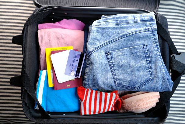 close-up of things, documents are stacked in a black open suitcase on the couch, concept of summer vacation, business trip, go on a long-awaited voyage - Фото, изображение