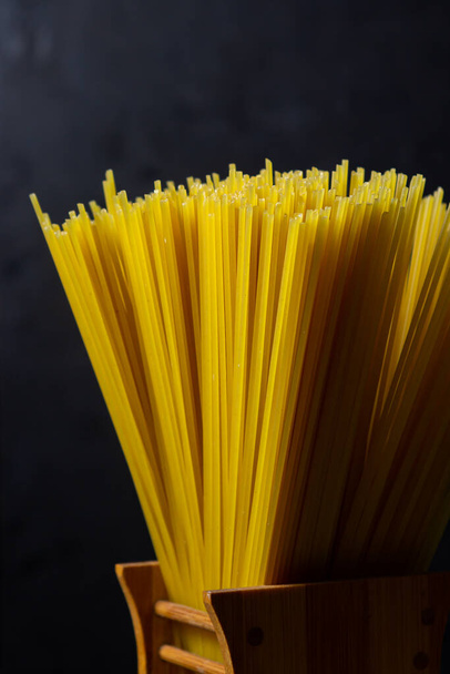 Trockene Spaghetti auf schwarzem Hintergrund. Traditionelle Nudeln aus nächster Nähe. Italienische Lebensmittel - Foto, Bild