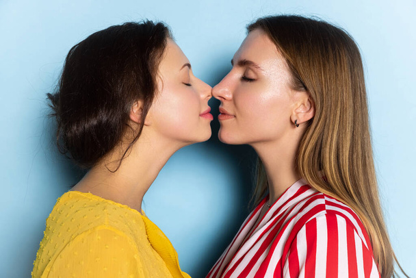 Close-up young girls, couple isolated on blue background. Valentines day celebration. Concept of emotions, love, relations, romantic holidays. - Foto, afbeelding