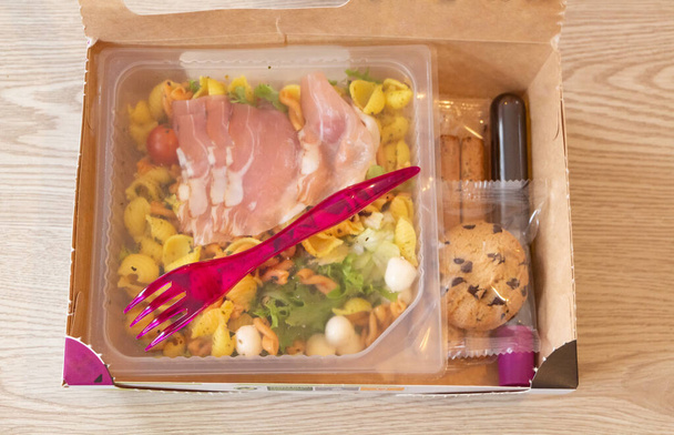 Ipari vegyes saláta, kenyérfa, öntet és süti kartondobozban - Fotó, kép