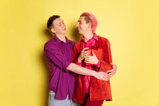 Portrait of young men, couple posing isolated on yellow background. Valentines day celebration. Concept of emotions, love, relations, romantic - Foto, Imagem